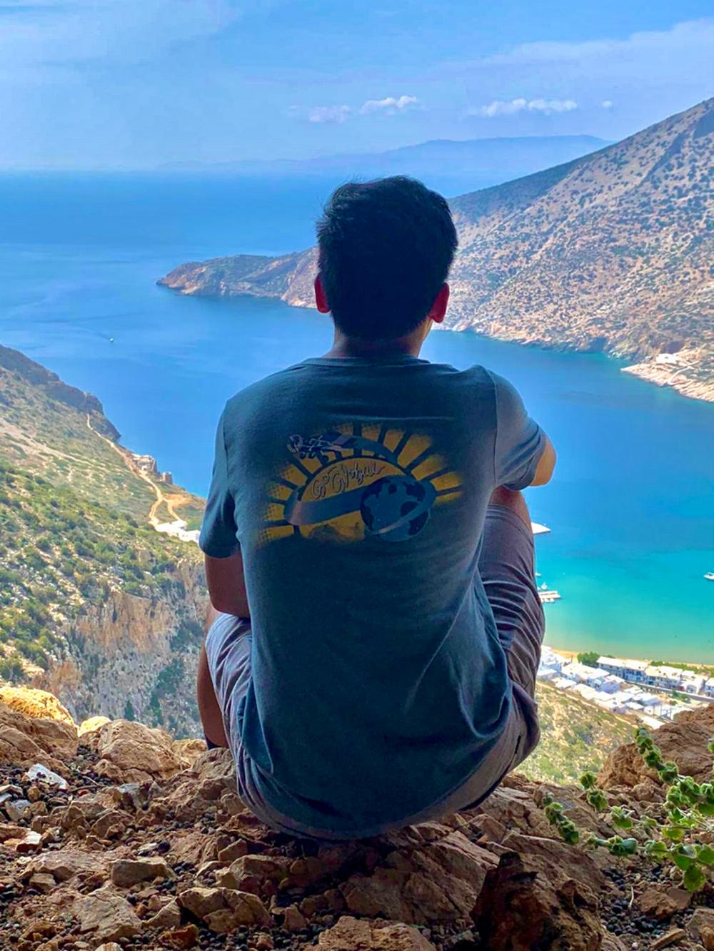 Study Abroad student displays Embry-Riddle flag in front of scenic river and distant mountains.